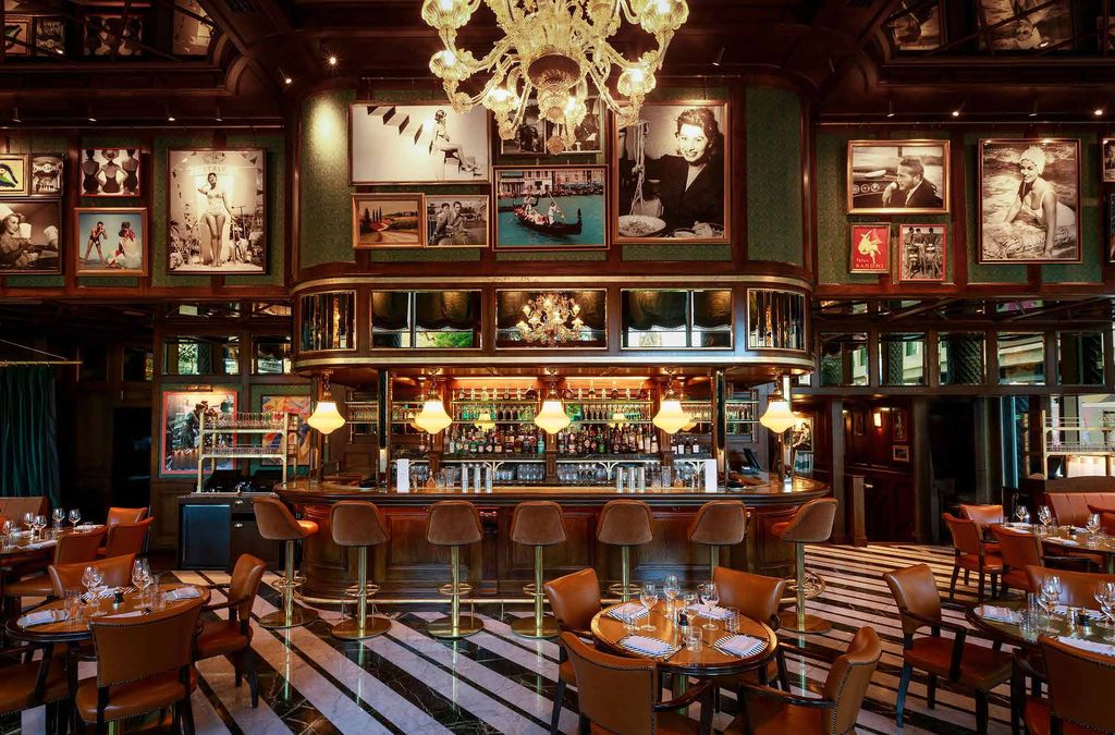 Harry's Bar: a curved timber and brass back bar with glass pendant lights, leather stools and a striped marble floor